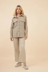 Camisa estilo leñador color beige con textura en espiga, de manga larga, con cuello clásico, cierre frontal con botones, dos bolsillos de parche con solapa abotonada en el pecho y puños abotonados. Confeccionada en lana fina sin teñir.