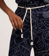 Pantalón recto de viscosa color azul marino con estampado lineal de follaje en blanco. Posee talle alto con trabillas y se ajusta con un cinturón de cuerda blanco. El pantalón es de corte cropped.