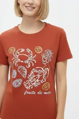 Remera marrón de manga corta y cuello redondo, de corte holgado, con estampado frontal alusivo a frutos del mar y texto "fruits de mer".