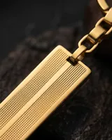 Llavero de acero con baño en oro, compuesto por un aro, una cadena de eslabones y una placa rectangular con textura grabada.