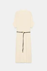 Vestido midi holgado de punto color crudo, con cuello subido, manga corta con vuelta y cinturón negro efecto piel con hebilla dorada.