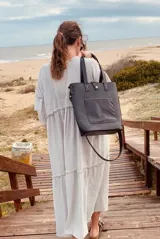 Bolso tipo matera de color negro, diseñado para transportar el equipo de mate con la funcionalidad de una cartera. Cuenta con un bolsillo exterior frontal, correas de hombro y una correa larga ajustable y extraíble. El interior está forrado con material impermeable.