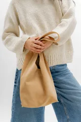Bolso tote pequeño de cuero color beige, con doble asa corta y diseño minimalista.