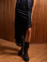 Pollera midi de terciopelo negro con corte asimétrico y detalle de encaje en el ruedo.