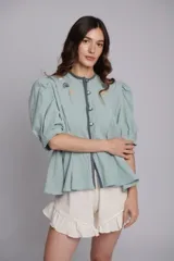 Chaqueta en tono menta confeccionada en tusor 100% algodón, con mangas balloon y bordados a mano de estrellas y figuras marinas. Presenta botones teñidos al tono en el frente y botones estrella en los puños.