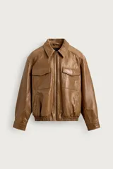 Cazadora de cuero marrón de corte regular fit, con cuello solapa, manga larga y cierre frontal de cremallera. Cuenta con bolsillos delanteros de plastrón con solapa en el pecho y elástico en el ruedo.