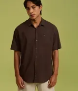 Camisa de corte relajado para hombre, confeccionada en una mezcla de cáñamo y algodón. Presenta cuello inglés, manga corta, cierre frontal con botones y un bolsillo en el pecho con una pequeña etiqueta aplicada.