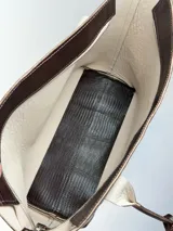 Cartera tipo tote de cuero genuino color marrón oscuro con textura de reptil. Cuenta con doble asa de hombro, cierre superior y un dije colgante de cuero a tono.