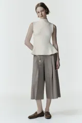 Top de punto sin mangas con cuello subido y diseño peplum con bajo evasé.