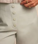Short de sastrería color rosado, de tiro alto con detalles de pinzas frontales y cartera abotonada con cuatro botones revestidos. Presenta diseño recto y estructurado.