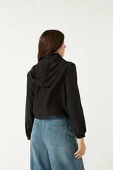 Campera deportiva corta color negro, con capucha ajustable y bolsillos frontales.