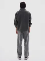 Buzo de sherpa color gris oscuro, con cuello alto y medio cierre frontal. Presenta un bolsillo ojal en el pecho con cierre y bolsillos laterales. Cuenta con cordón regulable en el ruedo para un ajuste personalizado.