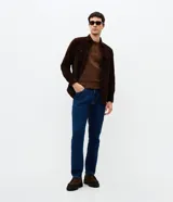 Pantalón de jean corte slim color azul oscuro, con cierre frontal de botón y cremallera, pasadores para cinturón y bolsillos funcionales.