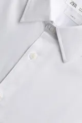 Camisa de corte slim fit confeccionada en tejido de algodón, con cuello italiano, manga larga con puños abotonados y cierre frontal de botones.