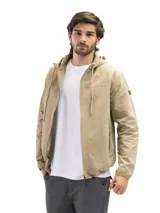 Campera rompevientos de nylon color beige, con capucha ajustable, cierre frontal, bolsillos laterales con cierre y puños elásticos.