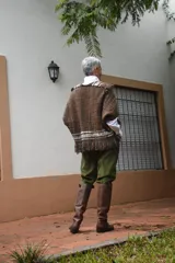 Capita artesanal de lana merino pura, color marrón con textura tejida y flecos decorativos en los bordes.