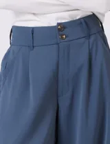 Pantalón palazzo de tiro alto en color verde militar, con diseño de doble abotonadura frontal, pinzas en la cintura y pierna ancha. Cuenta con cintura elástica en la parte posterior para mayor ajuste y bolsillos laterales funcionales.