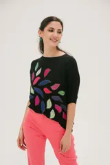 Remera negra de corte holgado con estampado de hojas de colores en el frente.