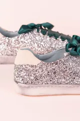 Zapatillas urbanas plateadas con glitter, puntera y talón en cuero blanco, cordones de raso verde esmeralda y suela blanca.