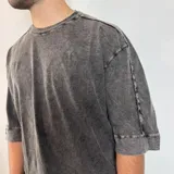 Remera de corte oversize en color verde oliva con efecto de lavado gastado. Presenta cuello redondo, mangas cortas con dobladillo ancho y costuras visibles.