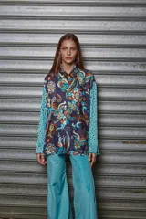 Camisa estampada con motivos paisley en tonos azul, marrón y naranja, con mangas largas en color celeste con lunares negros.