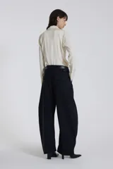 Pantalón negro de corte amplio con cinturón de cuero negro.