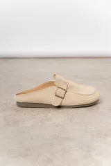 Zueco de cuero gamuzado color marrón, con diseño minimalista y elegante. Cuenta con una tira lateral con hebilla metálica regulable y plantilla acolchada. Su base es liviana y flexible.