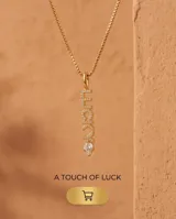 Collar de bronce dorado con cadena fina de eslabones y dije colgante vertical con la palabra "Lucky" incrustada de circonias y una piedra transparente en el extremo.