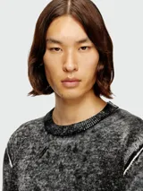 Buzo de tejido grueso con efecto jaspeado o acid wash en tonos de gris y negro. Presenta cuello redondo, puños y ruedo en tejido acanalado gris claro. Tiene un detalle de costura blanca en la sisa.