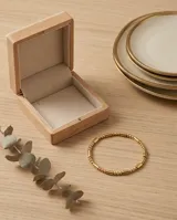 Pulsera esclava de acero con baño de oro, compuesta por una secuencia de cuentas esféricas y cilíndricas pequeñas.