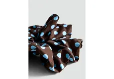 Colaless o scrunchie para el pelo de color marrón con estampado de lunares celestes.