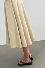 Vestido midi de gabardina en color beige, con cuello subido, manga corta y falda acampanada con caída fluida.