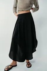 Pantalón fluido de tiro alto en color blanco, con pinzas delanteras, cintura elástica en la espalda y perneras anchas con aberturas laterales pronunciadas.