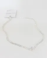 Collar tipo gargantilla en forma de V, confeccionado con cristales engarzados en estructura plateada. Presenta un diseño articulado con un cristal central de mayor tamaño en el vértice.