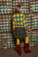 Sweater tejido de algodón con cuello alto marrón, diseño con rombos amarillos, verdes y azules, y bordado frontal de dos figuras.