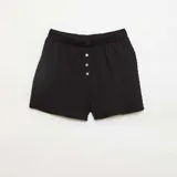 Short de punto gofrado color negro, con cintura elástica y cierre frontal decorativo con tres botones.