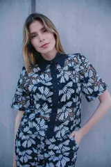 Conjunto de tres piezas compuesto por camisa de manga corta, pantalón de corte recto y top tipo bandeau. Todas las prendas presentan un diseño de encaje con estampado floral en blanco y negro.
