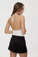 Top blanco de silueta ajustada, con escote drapeado, breteles finos y aplicación de pequeñas tachas metálicas.