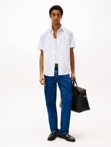 Camisa de hombre Tommy Hilfiger de manga corta, confeccionada en popelina de algodón con tecnología Flex, a rayas verticales blancas y celestes. Tiene cuello abotonado, corte regular y logo bordado en el pecho.