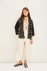 Kimono de corte holgado en color negro, con mangas tres cuartos y diseño bordado con motivos florales y detalles en hilo dorado. Presenta un cierre frontal anudado y forro interior.