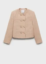 Chaqueta de tweed en color beige con diseño recto, cuello redondo y cierre frontal de doble botonadura con botones dorados. Presenta dos bolsillos de parche en el pecho y forro interior.