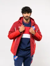 Campera de abrigo Umbro del Club Nacional de Football, con diseño de bloques de color en azul, blanco y rojo. Cuenta con capucha ajustable, cierre frontal y logo de la marca junto al escudo del club en el pecho.