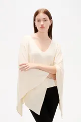 Poncho de tejido de punto color crudo con escote en V, diseño holgado y caída fluida.