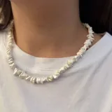 Collar corto tipo gargantilla compuesto por pequeñas piedras blancas irregulares, similar a la turquesa o cuarzo blanco, ensartadas en un hilo.