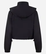 Campera cortavientos deportiva de corte cropped, color verde oscuro. Presenta capucha, cierre frontal con cremallera, mangas largas con puños elásticos y cordón ajustable en el ruedo.