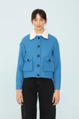 Chaqueta azul con bolsillos delanteros forrada, botones metálicos y cuello desmontable con corderito.
