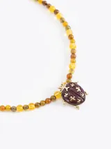 Collar de mostacillas de vidrio en tonos verdes y negros, con dije metálico en forma de mariquita azul oscuro con detalles plateados. Incluye cadena regulable de acero inoxidable.