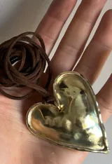 Collar con tres dijes de corazón irregular hechos a mano en alpaca o bronce, con tiento de gamuza negro y cuentas plateadas. El largo del tiento permite darle varias vueltas o usarlo largo.