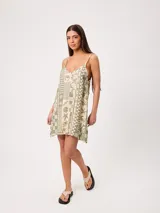 Vestido corto de algodón estampado, color verde, con tirantes finos y escote en V. Presenta un diseño holgado con estampado de patrones mixtos que incluyen motivos tropicales y geométricos.