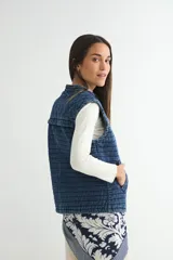Chaleco de denim acolchado con efecto lavado, diseño sin mangas, cierre frontal y bolsillos laterales.